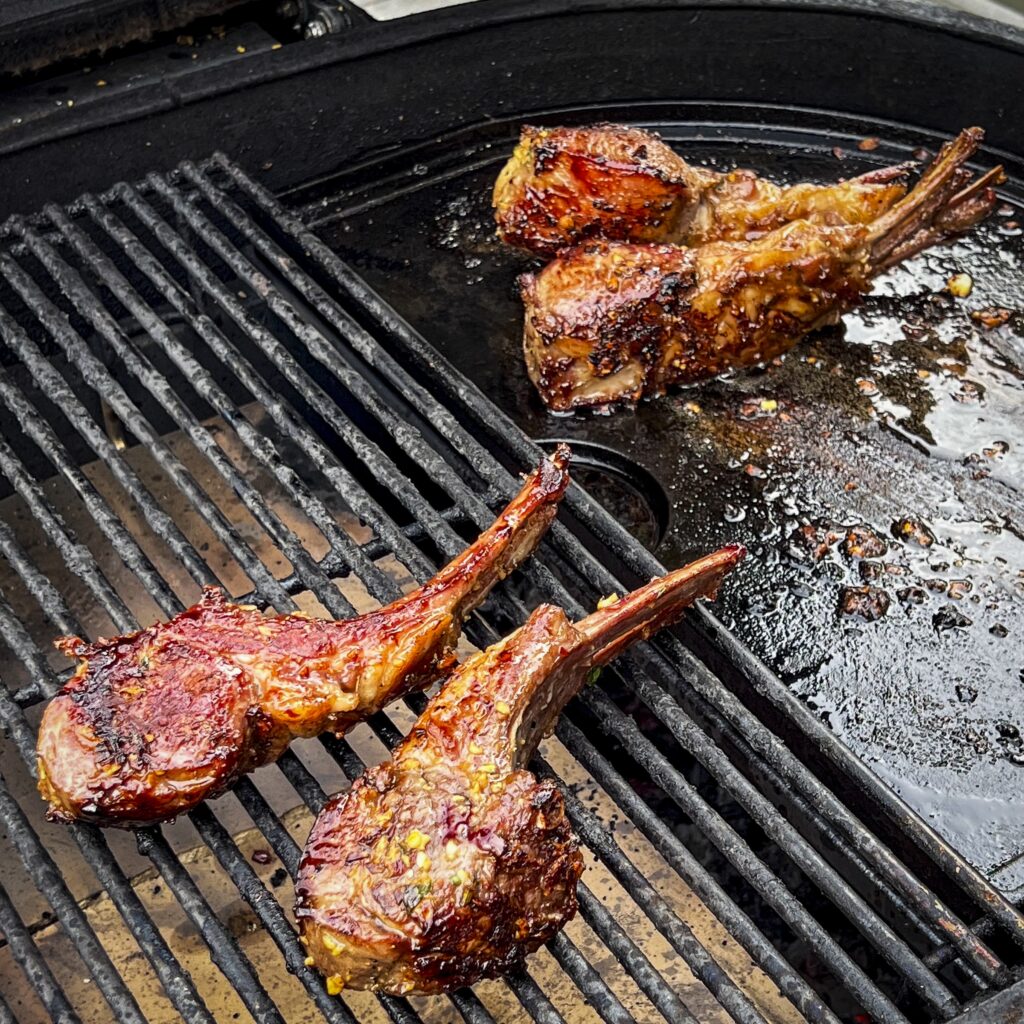 Four lamb chops are on the grill. 