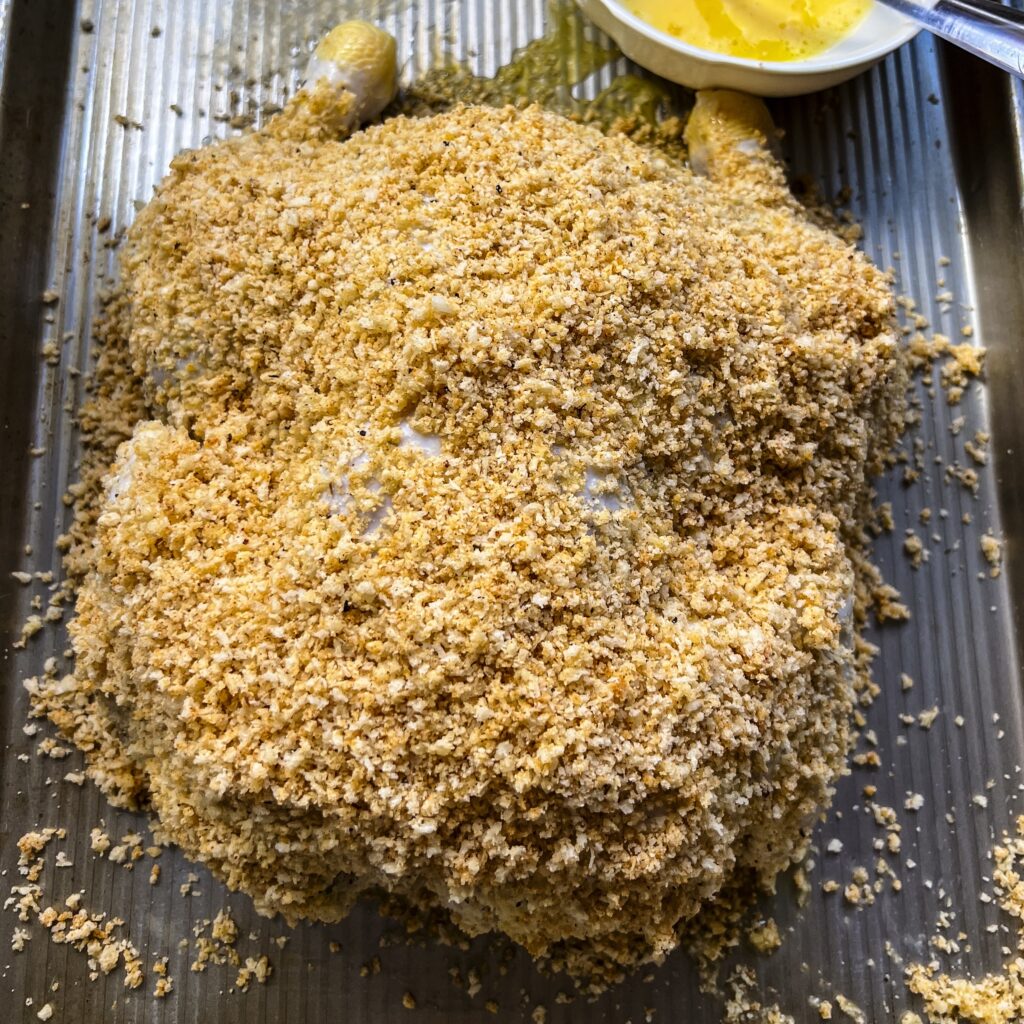 A golden brown parmesan panko crumb coat is on the backside of a chicken. 
