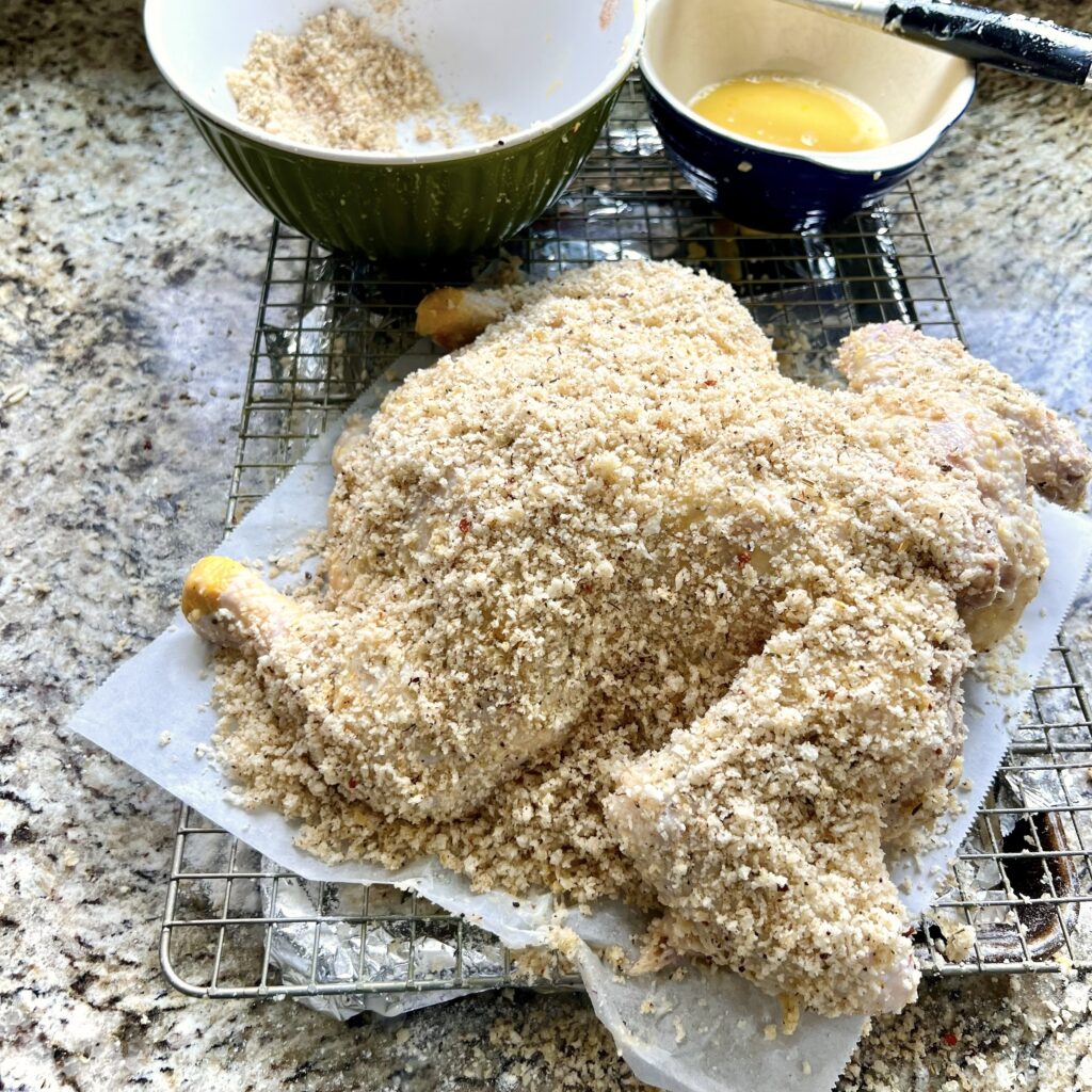 The backside of a chicken with unbaked crumb coat.