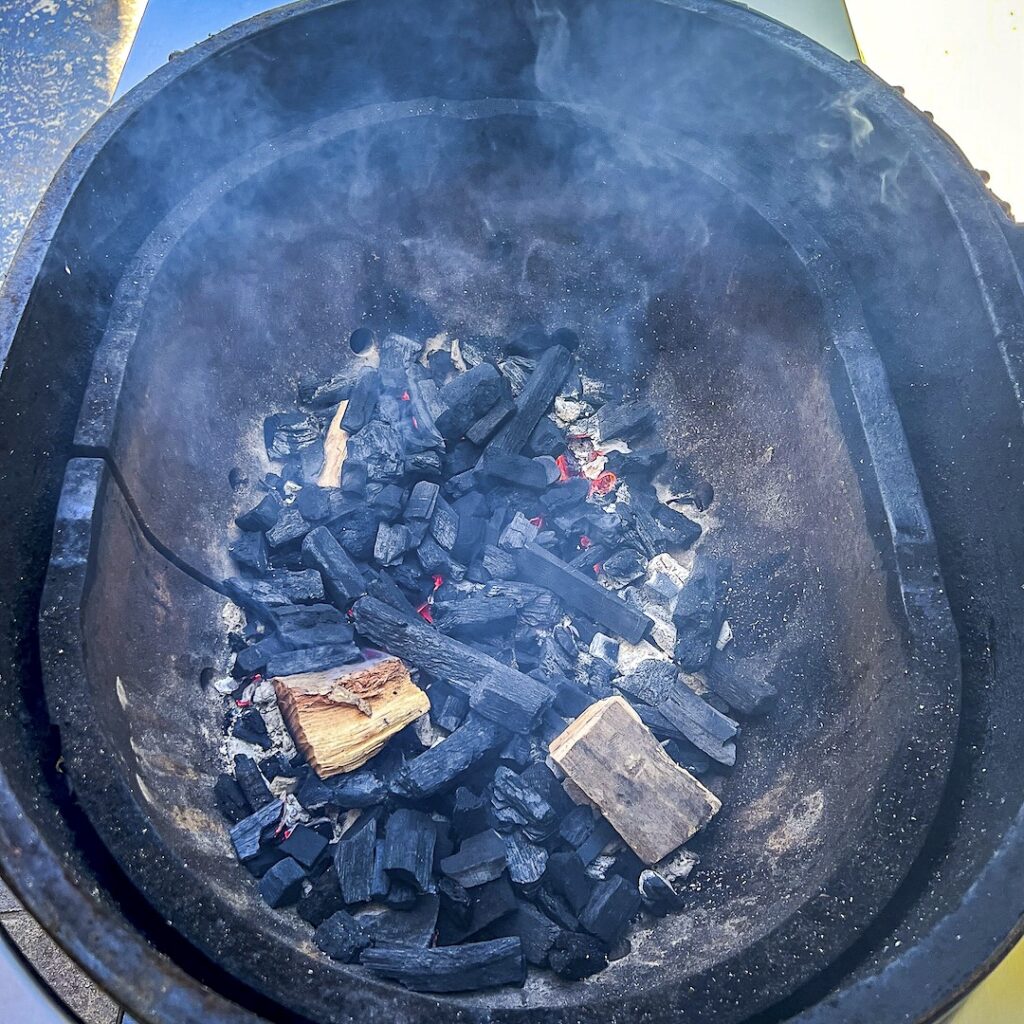 Two wood chunks are on a pile of lump charcoal.