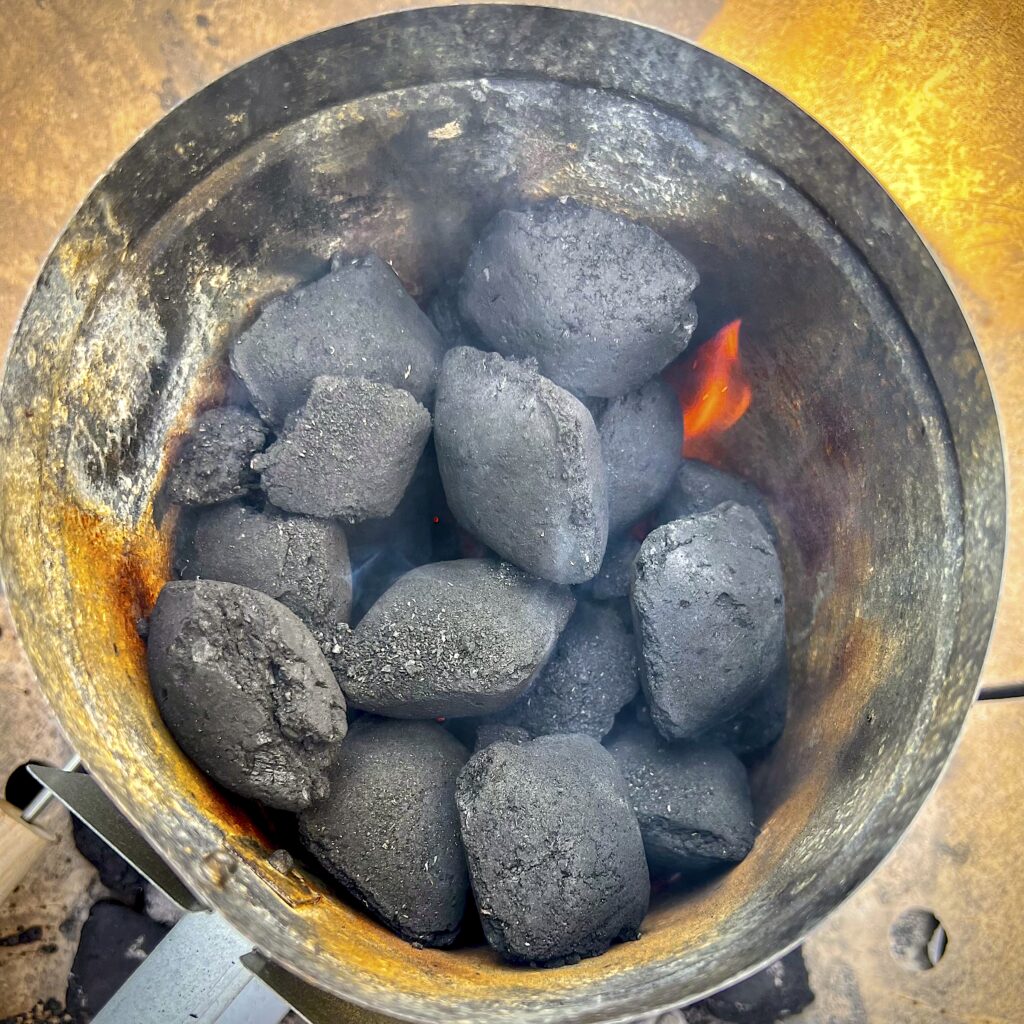 A smoking chimney is filled with briquets.