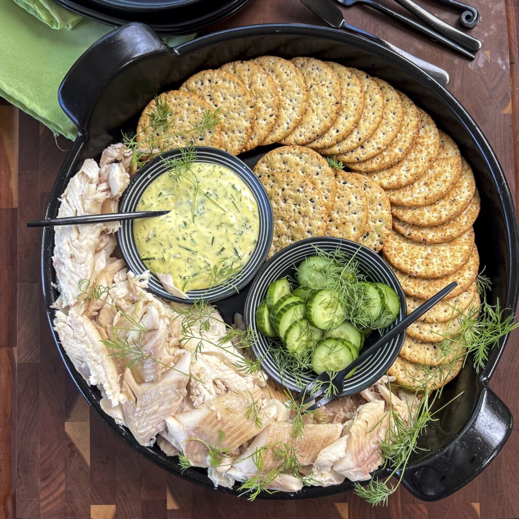 A platter of smoked trout with cucumbers and mustard dill cream sauce is ready to serve. 