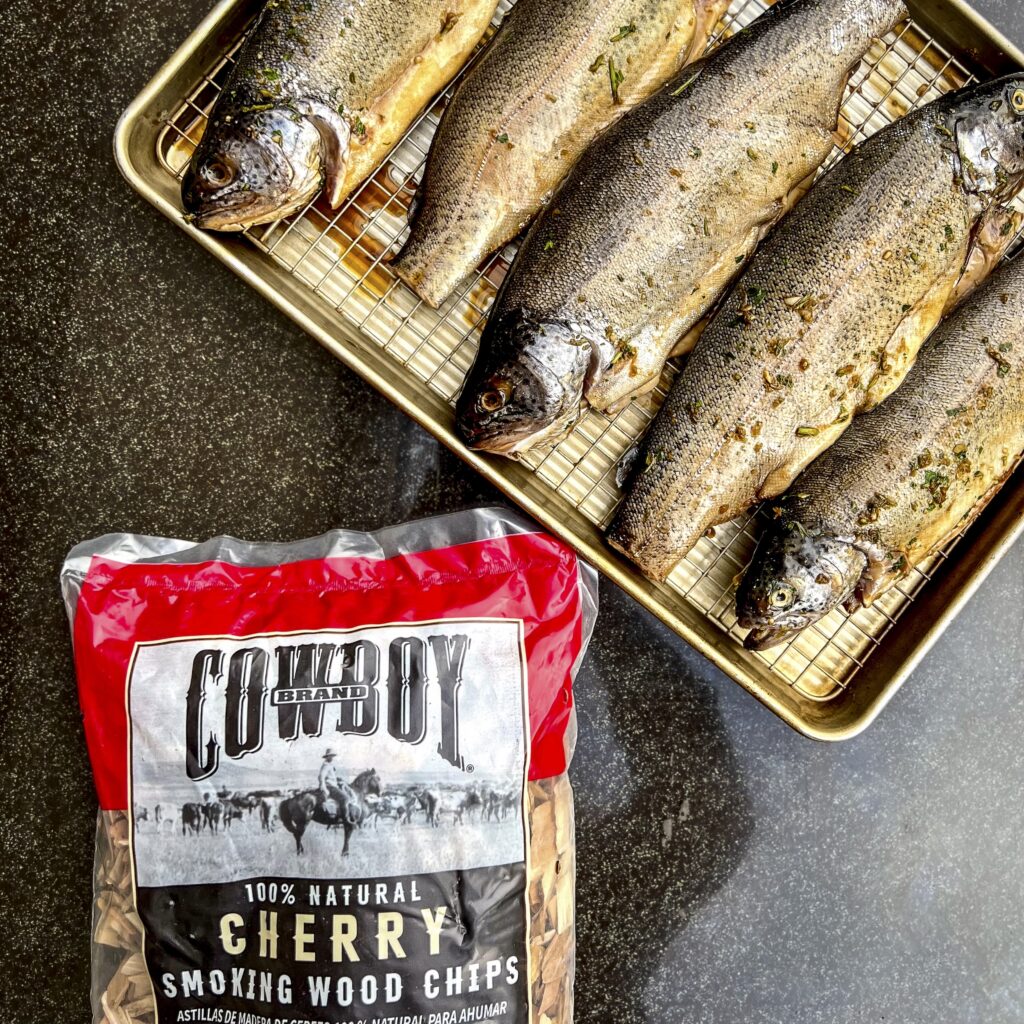 A bag of Cowboy Brand Cherry Wood Chips is next to 5 trout that have been brined. 