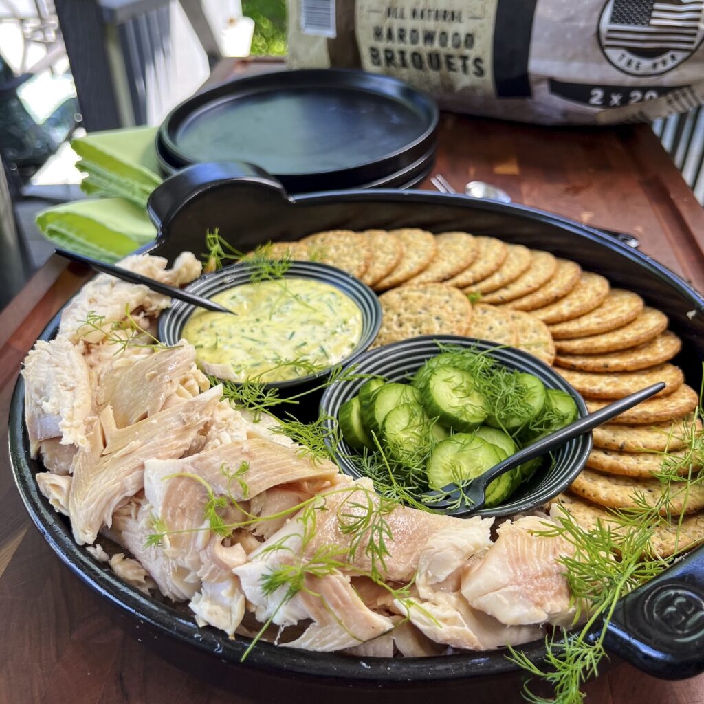 Time to eat from a platter of crackers, trout, mustard dill sauce and cucumbers.